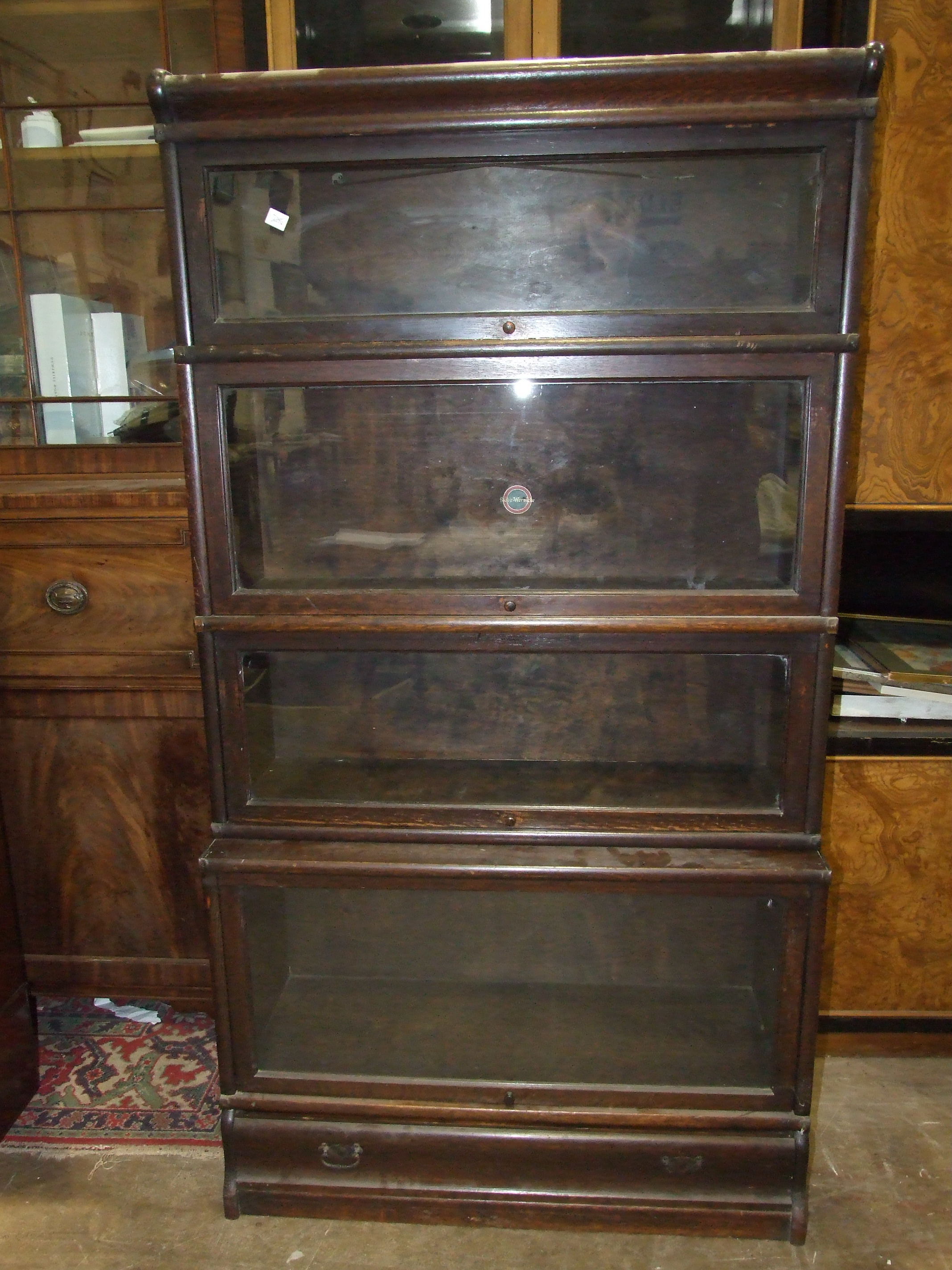 An oak four-tier Globe Wernicke bookcase, with up-and-over glass doors and drawer beneath, 87cm