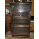 An oak four-tier Globe Wernicke bookcase, with up-and-over glass doors and drawer beneath, 87cm