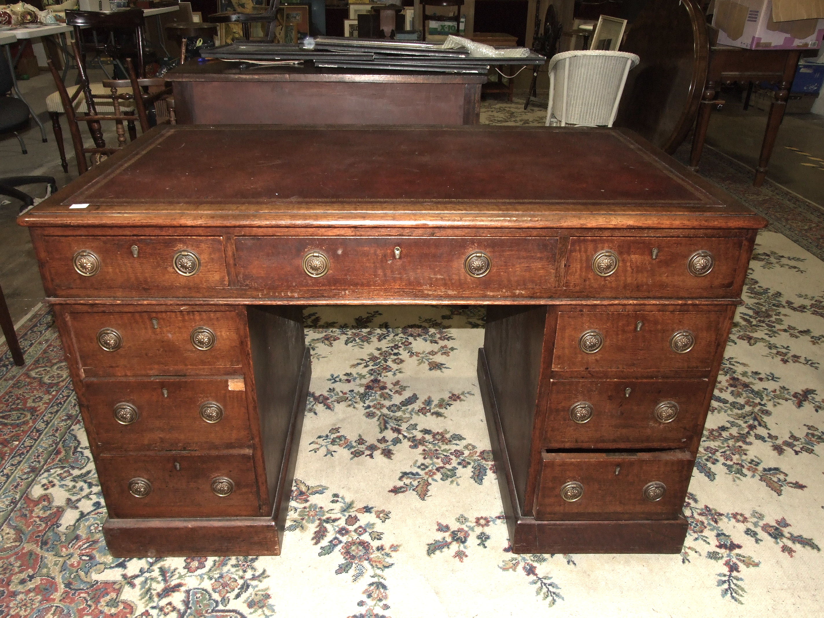 An Edwardian oak knee-hole desk, the top inset with writing surface above three frieze and six