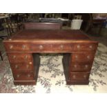 An Edwardian oak knee-hole desk, the top inset with writing surface above three frieze and six