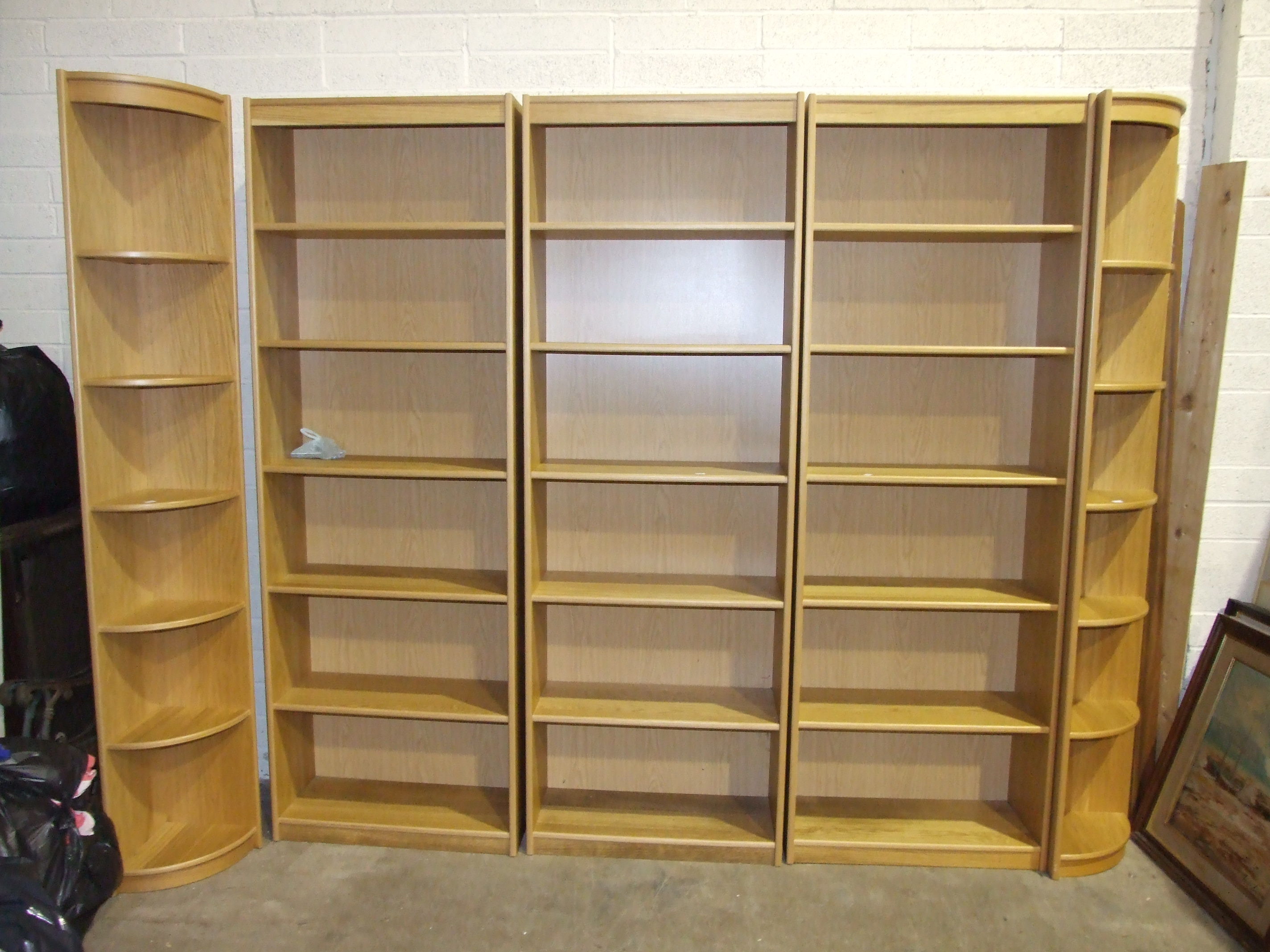 A large modern run of oak-effect shelving/bookcase shelves, with corner end sections, 287cm wide,