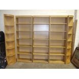 A large modern run of oak-effect shelving/bookcase shelves, with corner end sections, 287cm wide,