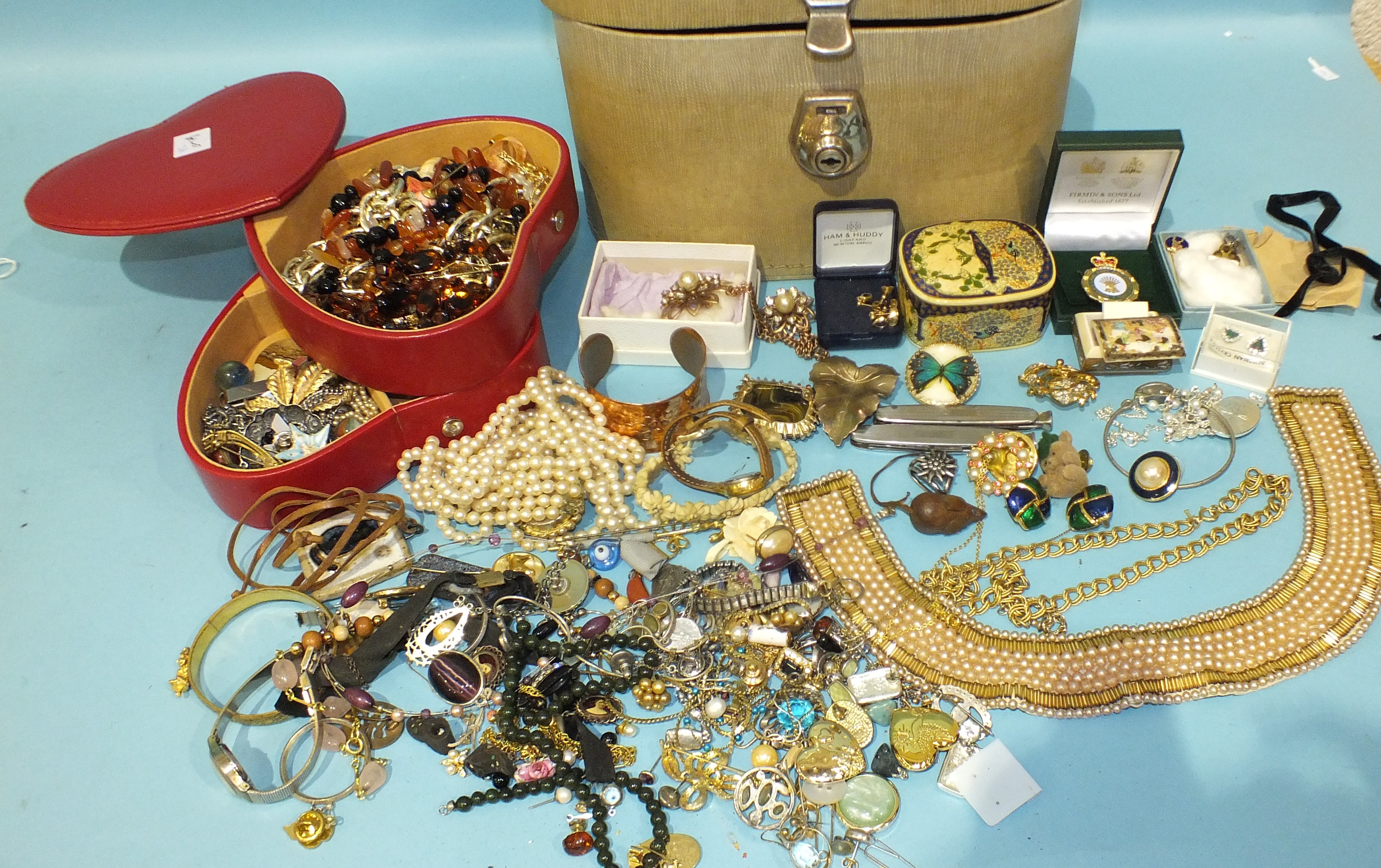 A quantity of costume jewellery in a heart-shaped jewellery case and a vanity case.