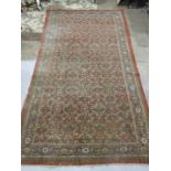 A large mid-20th century Oriental carpet with overall foliate symmetric pattern on red ground, (worn