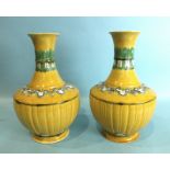 A pair of Chinese yellow ground baluster vases with bands of polychrome moulded decoration,