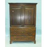 An antique oak linen press/wardrobe, having a pair of panel doors above a false drawer and two