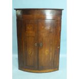 A George III oak and mahogany-banded hanging corner cabinet, the doors inlaid with butterflies, 80cm