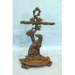 A cast iron stick or umbrella stand in the form of an oak tree branch with a dog seated at its base,