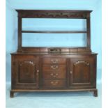 A Georgian oak dresser, the base fitted with four central graduated drawers flanked by cupboard