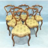A set of six Victorian walnut carved balloon-back dining chairs, with serpentine upholstered seats