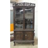 A 19th century oriental hardwood display cabinet profusely carved overall with fruiting vines, the