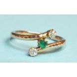 An emerald and diamond cross-over ring, claw-set a square-cut emerald between two old-cut