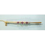 A 9ct gold bar brooch collet-set three pink tourmalines and two seed pearls, 65mm long, 3g.