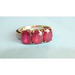 A ruby ring claw-set three oval rubies between diamond point-set shoulders, in 9ct gold mount,