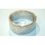A silver hinged bangle with engraved floral decoration, Chester 1959, 50g.