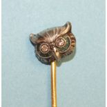 An Edwardian stick pin in the form of an owl's head, with diamond-set eyes, in white metal face