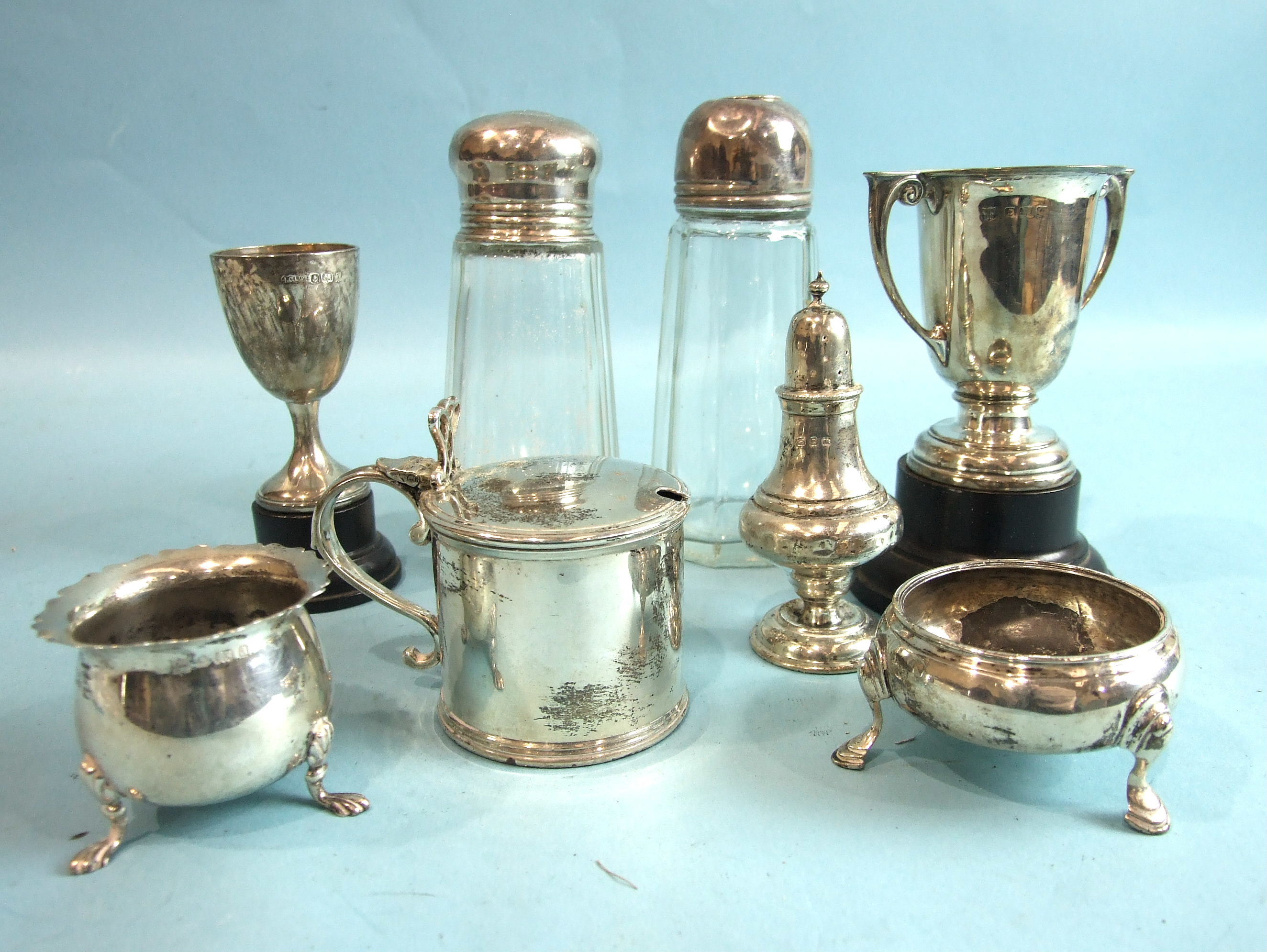 A plain cylindrical mustard with hinged lid, London 1928, two silver-topped glass sugar