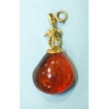 An unusual amber pendant, the gold finial in the form of three sea horses, on bale and ring-bolt,