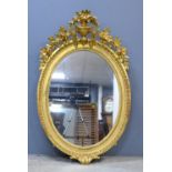 Gilt framed oval mirror with vase and floral surmount,