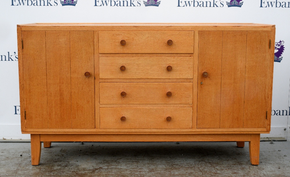 Heal & Sons, a golden oak sideboard in Cotswold School manner, with two plank panelled cabinets