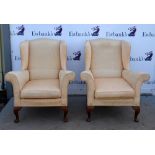 Pair of cream wing back arm chairs .