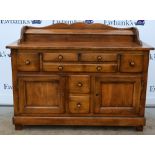 Modern oak dresser with raised back over five drawers and cupboards, .