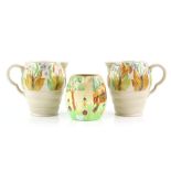 Clarice Cliff pair of jugs with leaf and fruit decoration, 19.5cm and a Shorter cottage jug .