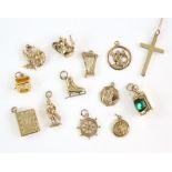Group of twelve gold charms, including thistles, well, bible, teapot, ice skate, lamp, harp, figure,