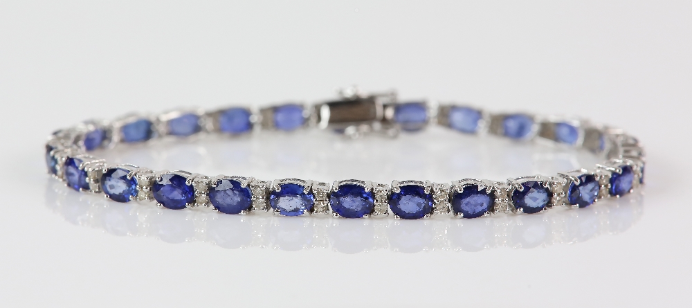 Sapphire diamond line bracelet; twenty-six oval faceted sapphires are four-claw set and alternated