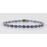 Sapphire diamond line bracelet; twenty-six oval faceted sapphires are four-claw set and alternated