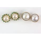 A pair of mabe pearl earrings, 13mm in diameter, set in a diamond and emerald surround, mounted in