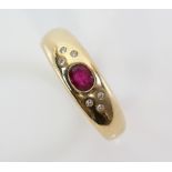 Modern gold band ring inset with a ruby and six small diamonds, marks for 18 ct gold, ring size