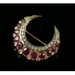 Early 20th C ruby and diamond gold crescent brooch, set with eleven round faceted rubies, the
