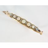 Early 20th C oval hinged gold bangle, set with seven graduated round cabochon cut opals and twelve