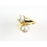 Gold crossover ring set with two pearls in unmarked gold testing as 18 ct, ring size M.