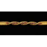 Cartier gold bracelet of concave basket work links, the central twist set with round faceted rubies,