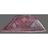 Persian red ground carpet with multiple borders the centre with foliate forms 230cm wide. .