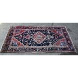 Persian blue ground rug with a large central red medallion, repeating floral motifs, multiple