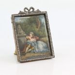 Erotic portrait miniature depicting a man and woman leaning against a wall, in paste set frame