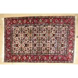 Persian rug with cream ground, repeating floral forms, pink floral border, 136cm x 85cm,. .