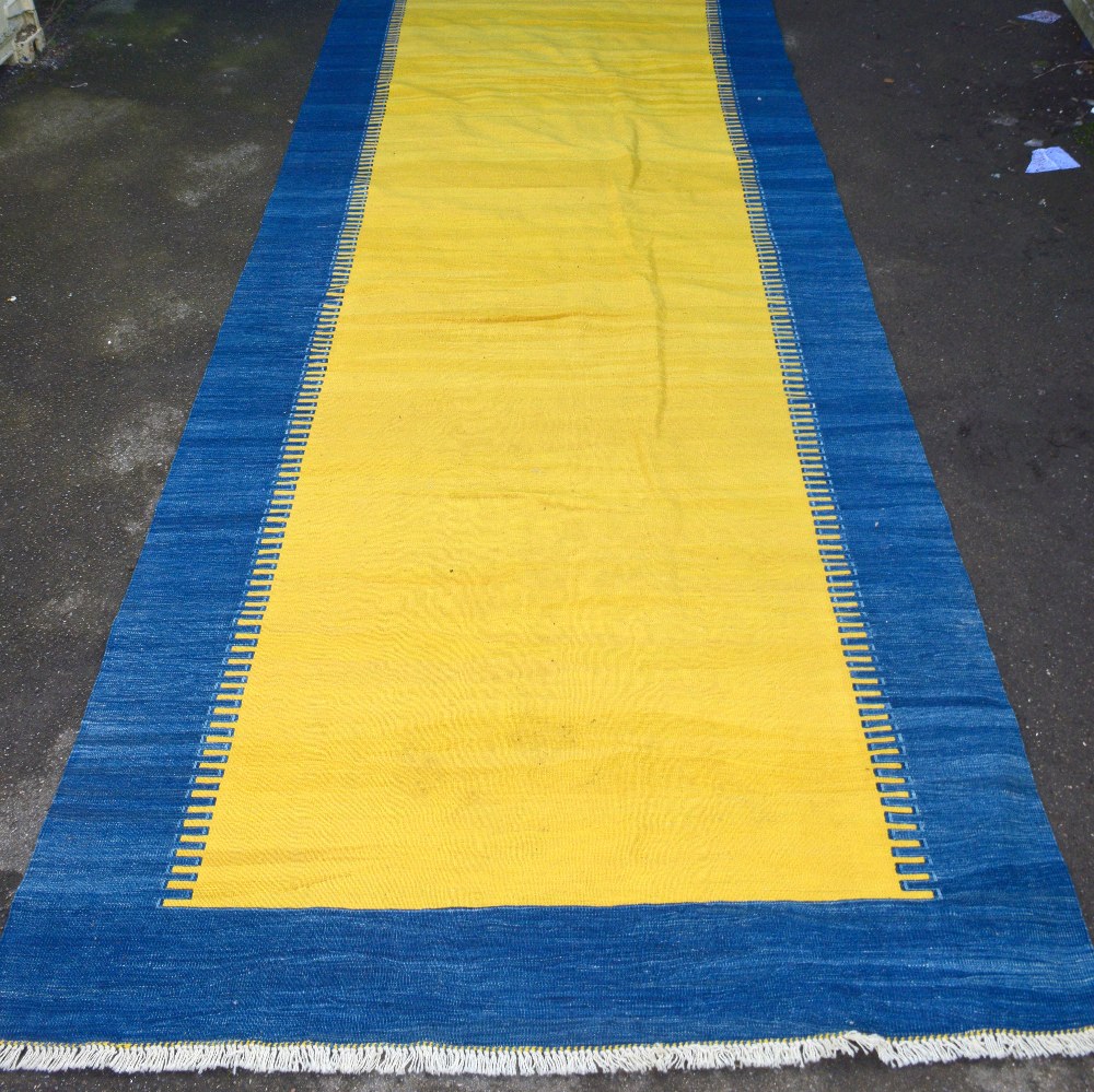 Modern yellow ground rug with a blue border,. .
