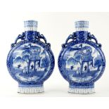 A pair of blue and white pilgrim flasks; each one about 30 cm high, and decorated with scholars