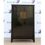 A Chinese black-lacquered cabinet of typical trapezoid form; the hinged doors opening to reveal a