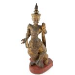 A Burmese Buddhist, or other, gilded wood figure on a shaped red-lacquered stand; the right hand