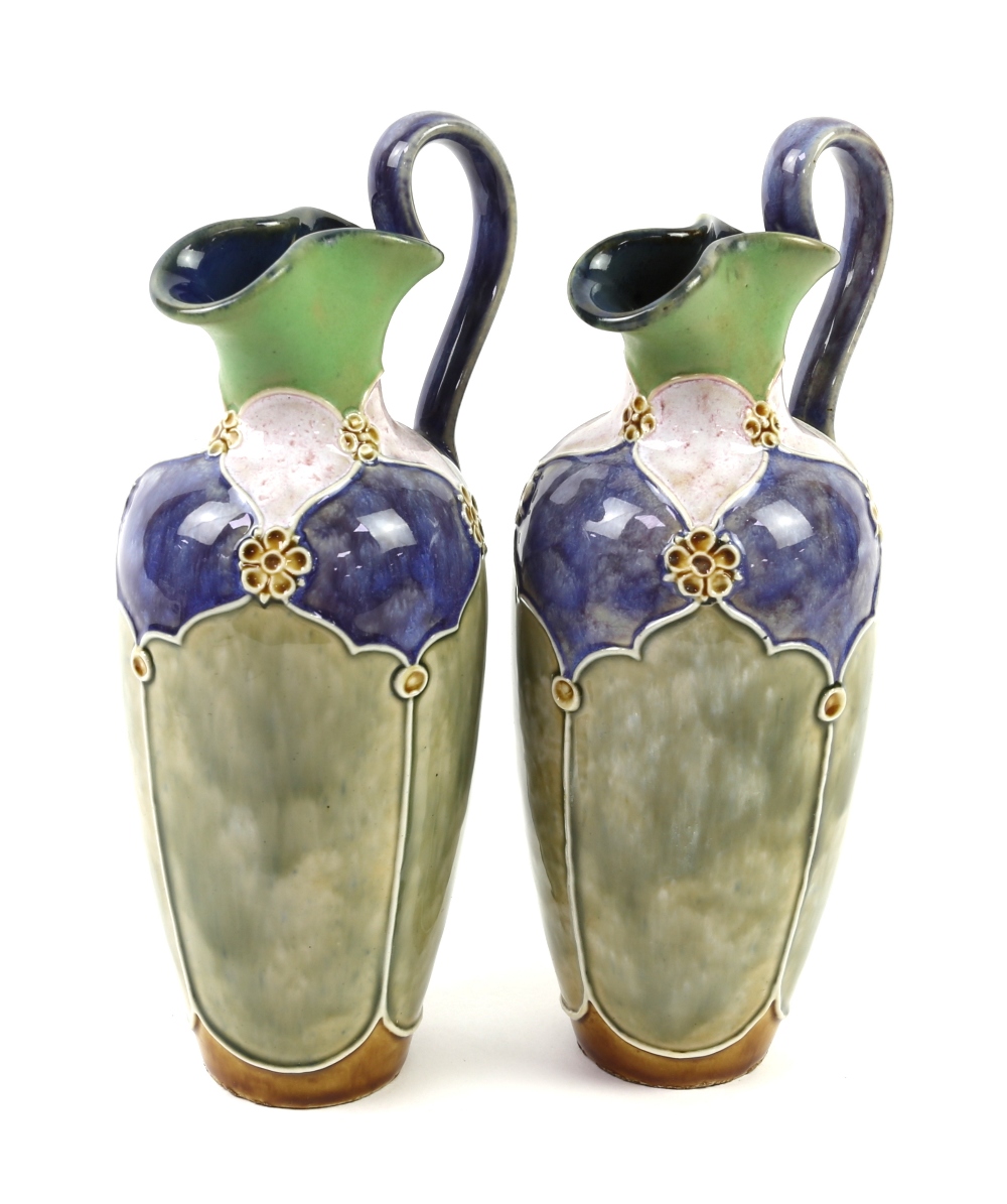 Pair of Royal Doulton jugs by Florrie Jones, 23cm high. One jug has a 3.5 cm firing crack to the rim