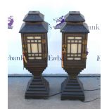 Pair of Chinese wooden floor standing lamps, pagoda tops above paper lined panels on stepped