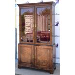 A 19th century figured walnut glazed bookcase, moulded cornice above glazed doors revealing velour