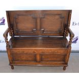 Oak monks bench with floral carved and panelled sides and barley twist supports, on turned feet,