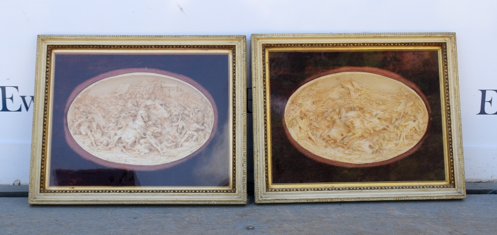 Pair of moulded reliefs depicting battle scenes, in glazed gilt wood frames, . Size