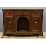 Oak dresser base, with three drawers and two cupboard doors carved with masks and scrolling foliage,